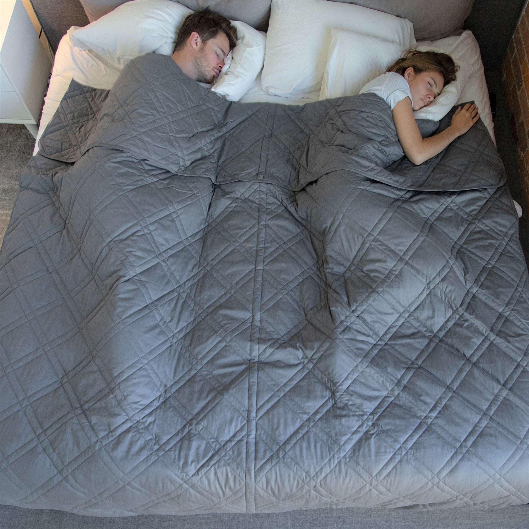 Two people sleeping in bed with a gray blanket.